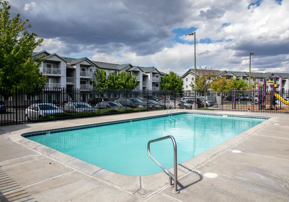 pool situated in front of a modern apartment building at Heron Creek Apartments in Moses Lake, Washington