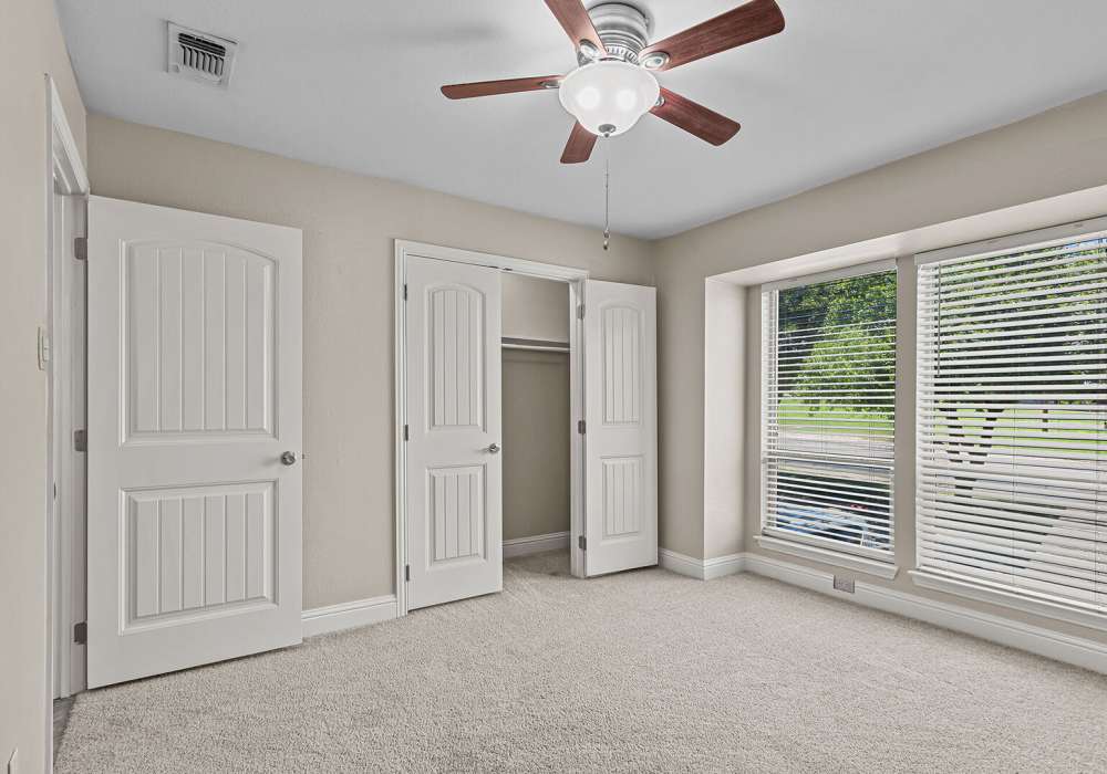 Apartment bedroom with a ceiling fan and back door at Courtyard Apartments And Storage in Granbury, Texas
