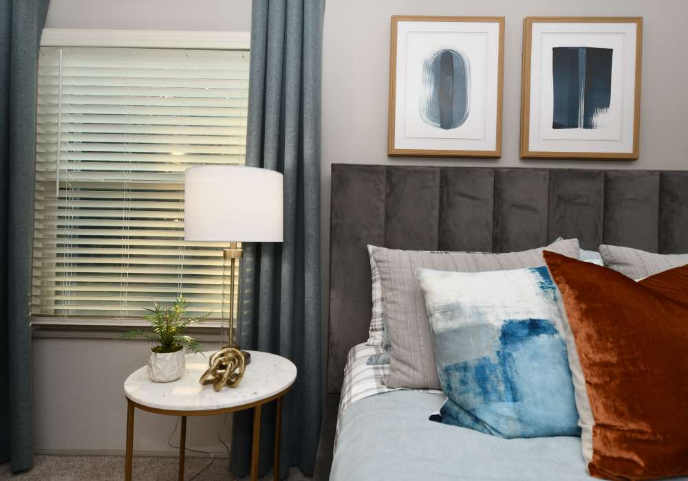 Bed with throw pillows, night stand and a window at Ascent Apartment Homes in Asheville, North Carolina