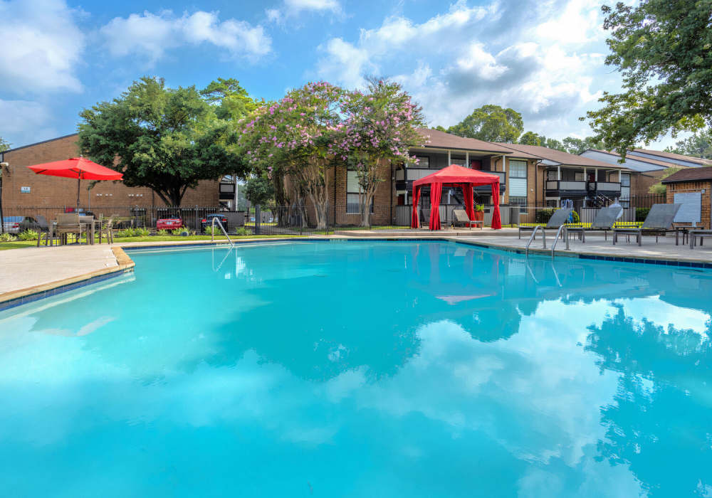 Swimming pool with lounge chairs and surrounded by buildings at Rayfords Edge Apartments in Spring, Texas