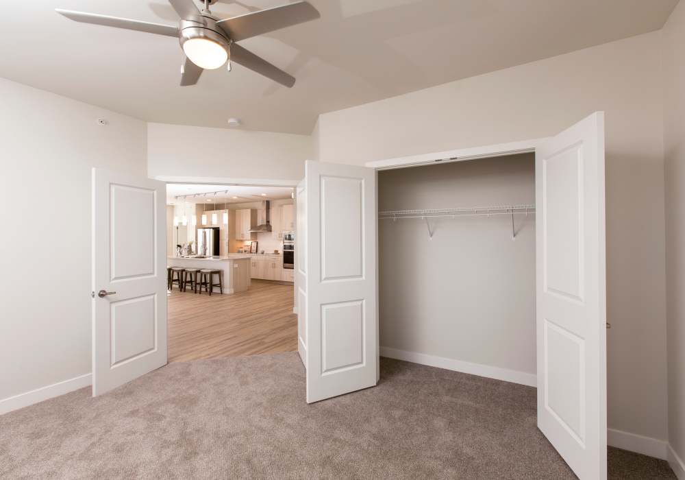 Kitchen view from empty bedroom with carpet flooring and ceiling fan at Altair At The Heights in Richmond Heights, Missouri