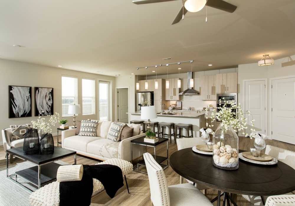 An open and spacious living room with couches adjacent to the kitchen and dining area at Altair At The Heights in Richmond Heights, Missouri