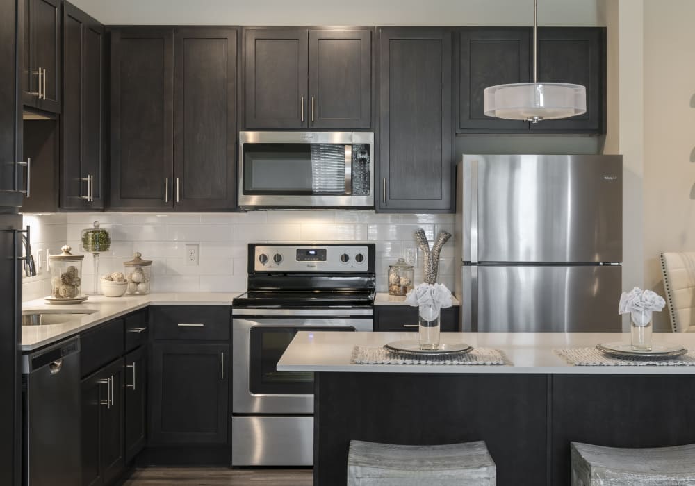 Stainless steel oven and dishwasher, sink and hardwood style flooring at Altair At The Preserve in O'Fallon, Missouri