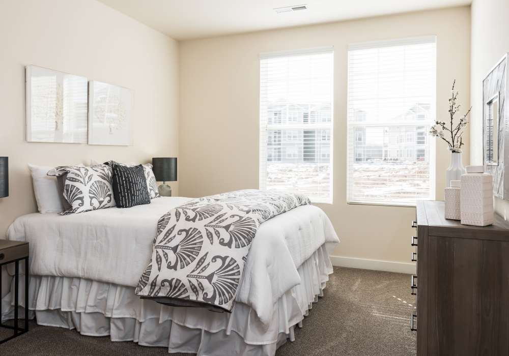 A king-sized bed in an apartment bedroom at Altair At The Preserve in O'Fallon, Missouri