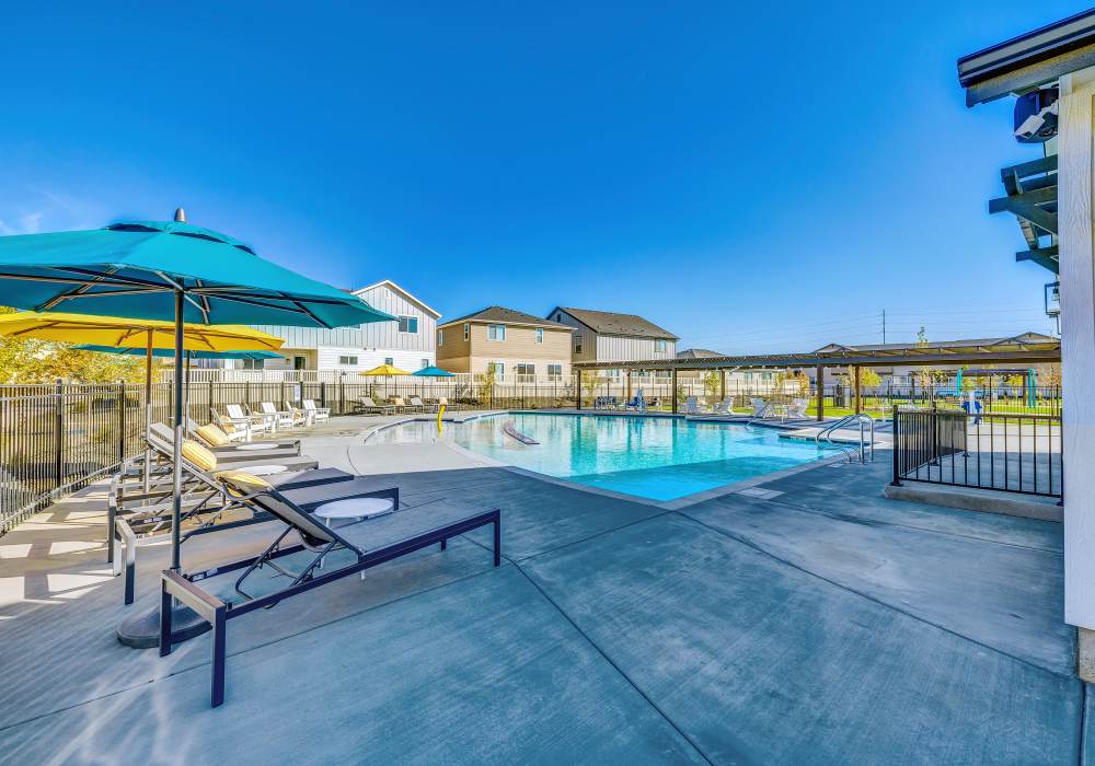 Community pool featuring lounge chairs & umbrellas at BB Living at The Oaks in Meridian, Idaho