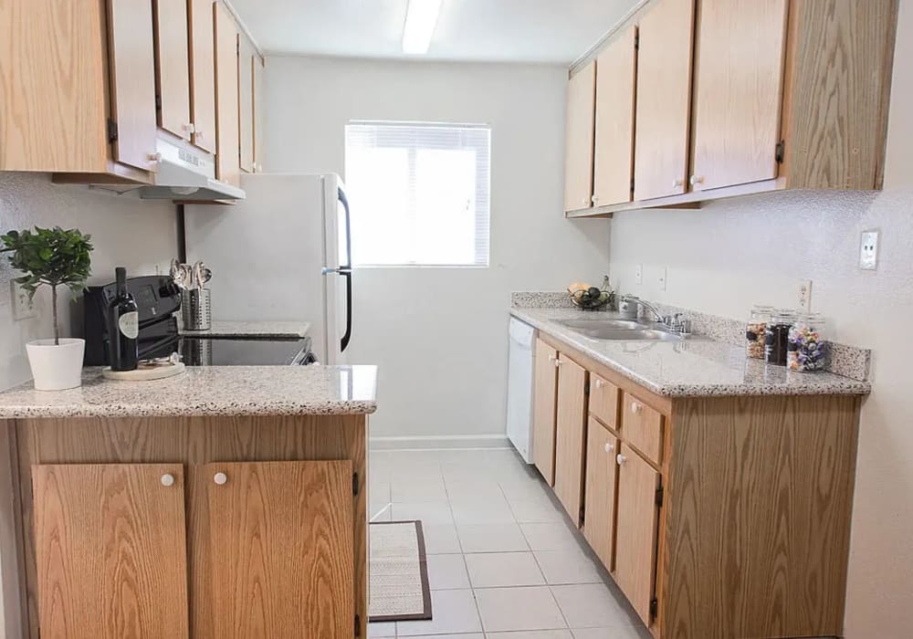 Kitchen with granite counters with wooden cabinetry at Walnut Apartments in Santa Rosa, California