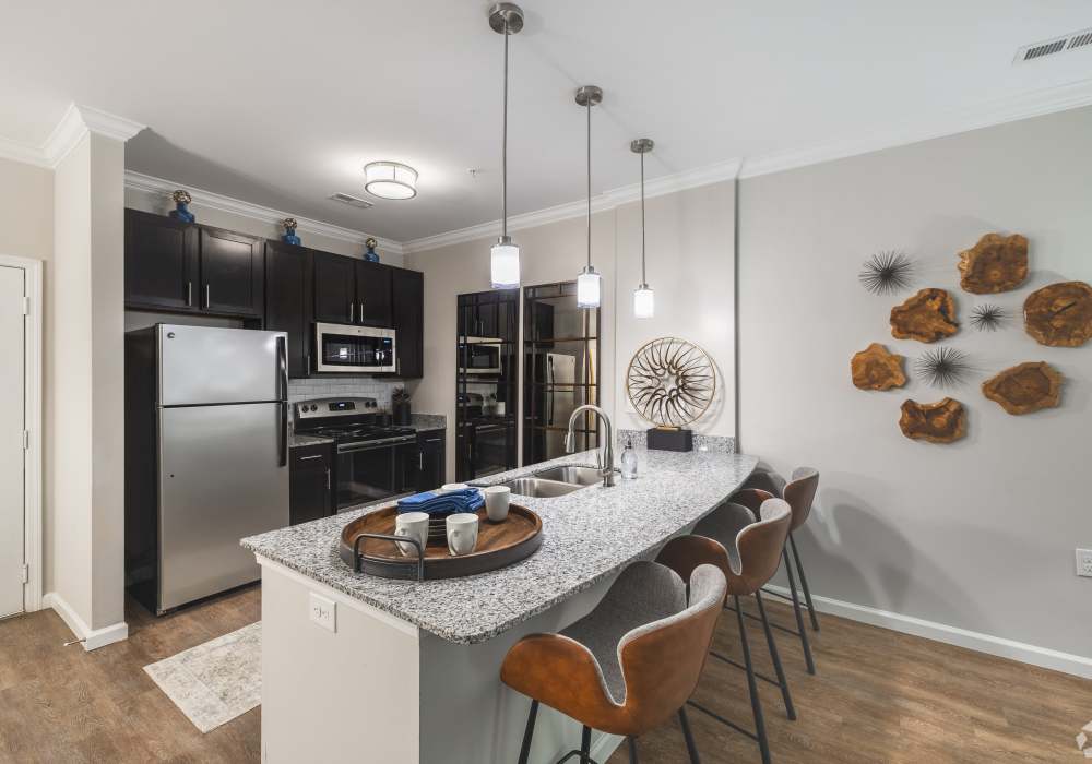 Fully-equipped kitchen with stainless steel appliances and island with bar chairs and pendant lights at Harborstone in Ladson, South Carolina
