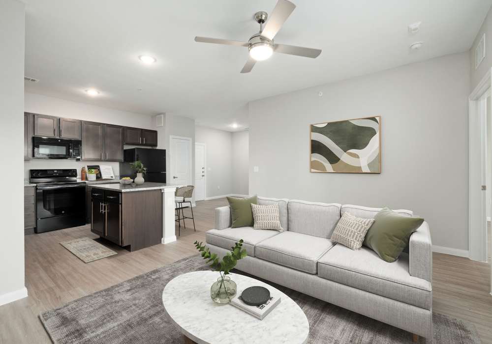 Living room with a couch and kitchen in the background at The Janson in Del Valle,Texas