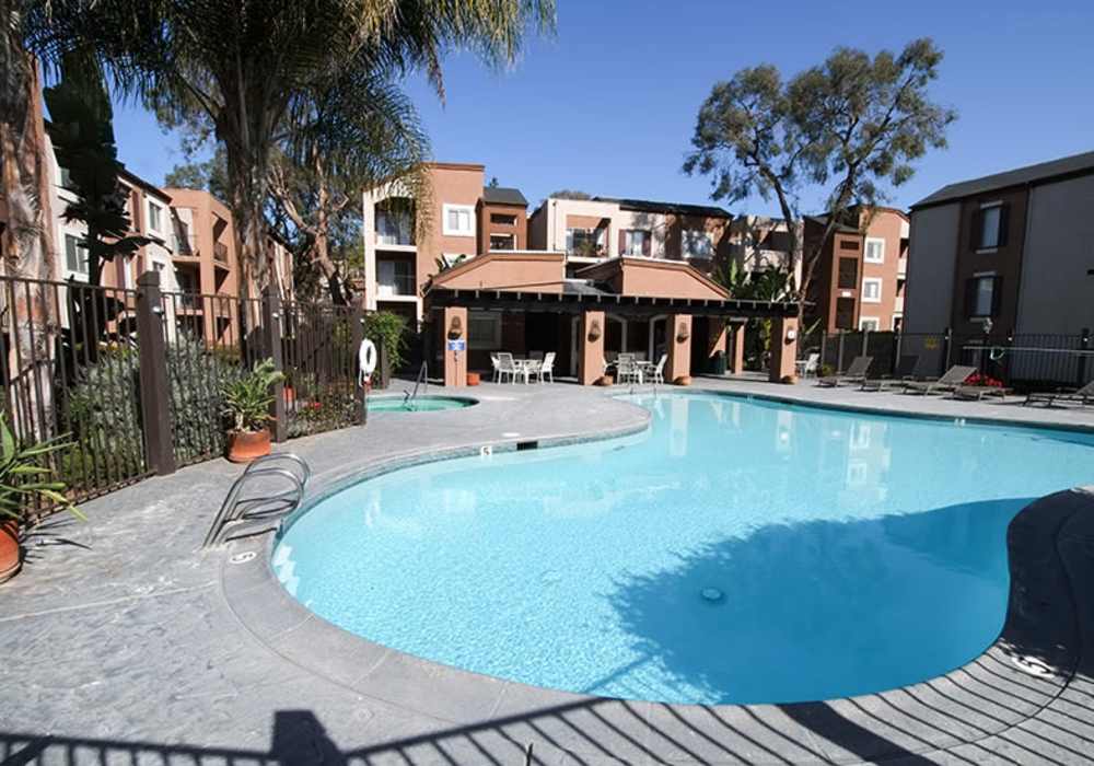 Discover your oasis with a sparkling water pool surrounded by lush landscaping at River Run Village in San Diego, California