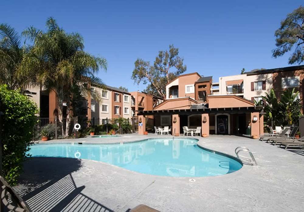 Revel in the inviting charm of this property featuring a sparkling water pool surrounded by lush landscaping and cozy lounging areas at River Run Village in San Diego, California