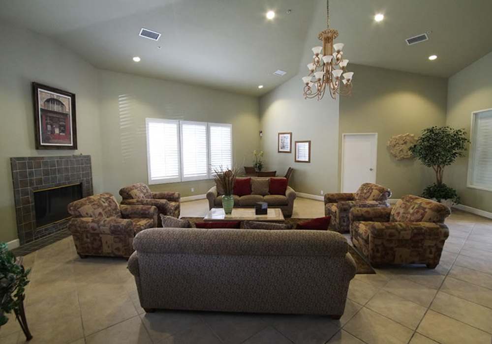 Spacious living area featuring cozy seating around a charming fireplace and elegant chandelier at River Run Village in San Diego, California