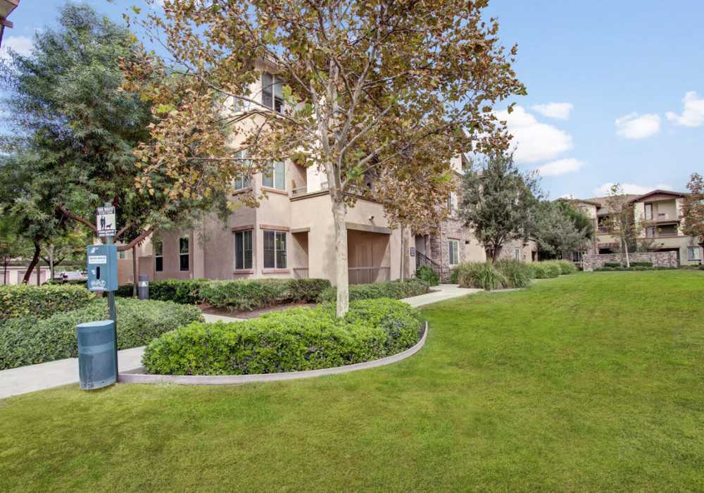 Exterior view of an apartment nestled amidst lush green grass and trees at Rivers Edge in Lake Elsinore, California