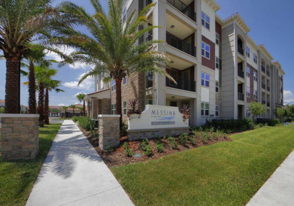 Building with name board and trees at Messina Luxury Apartments in New Smyrna Beach, Florida