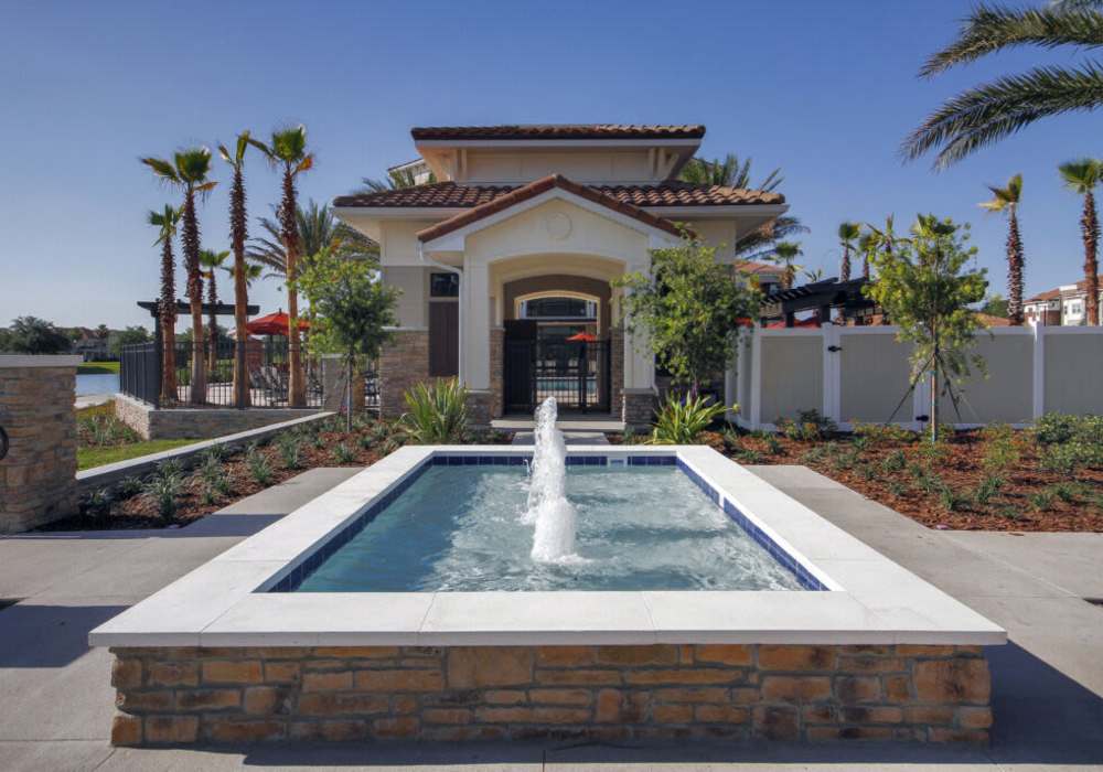 Inviting entrance with fountain and lush tropical landscaping at Messina Luxury Apartments in New Smyrna Beach, Florida