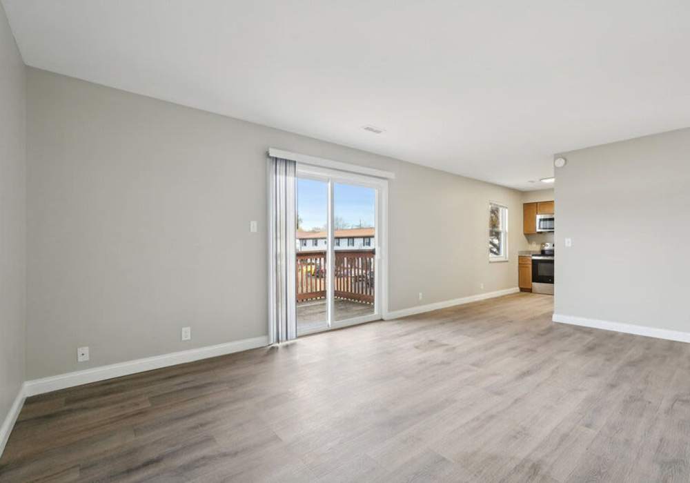Unfurnished living room with wooden flooring and kitchen view at Charleston Square Apartments in Columbus, Indiana