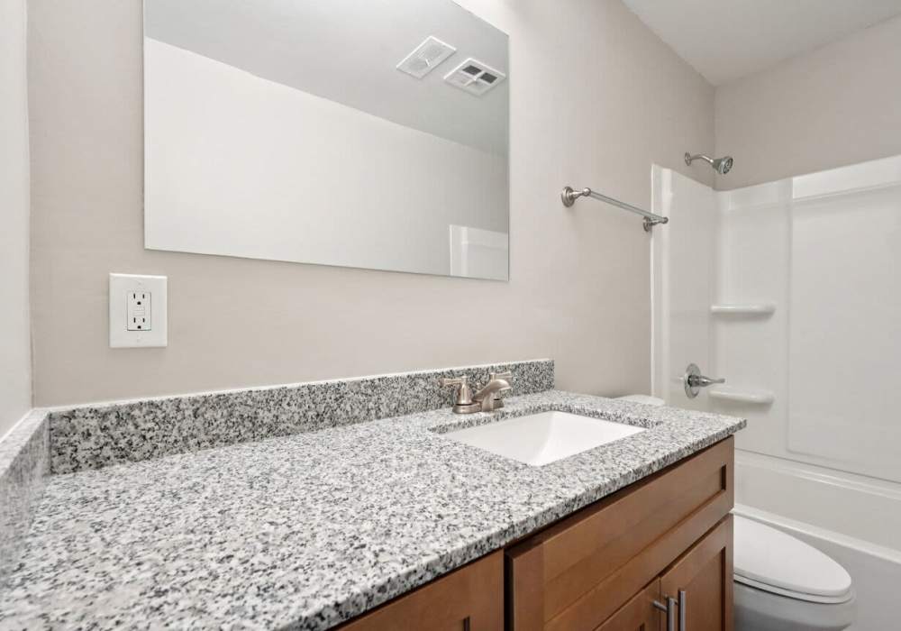 Bathroom with toilet large mirror and large mirror at Charleston Square Apartments in Columbus, Indiana