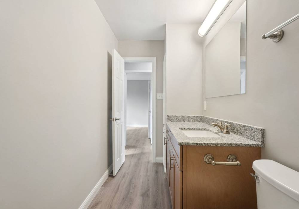 Bathroom with wooden cabinets and toilet large mirror at Charleston Square Apartments in Columbus, Indiana