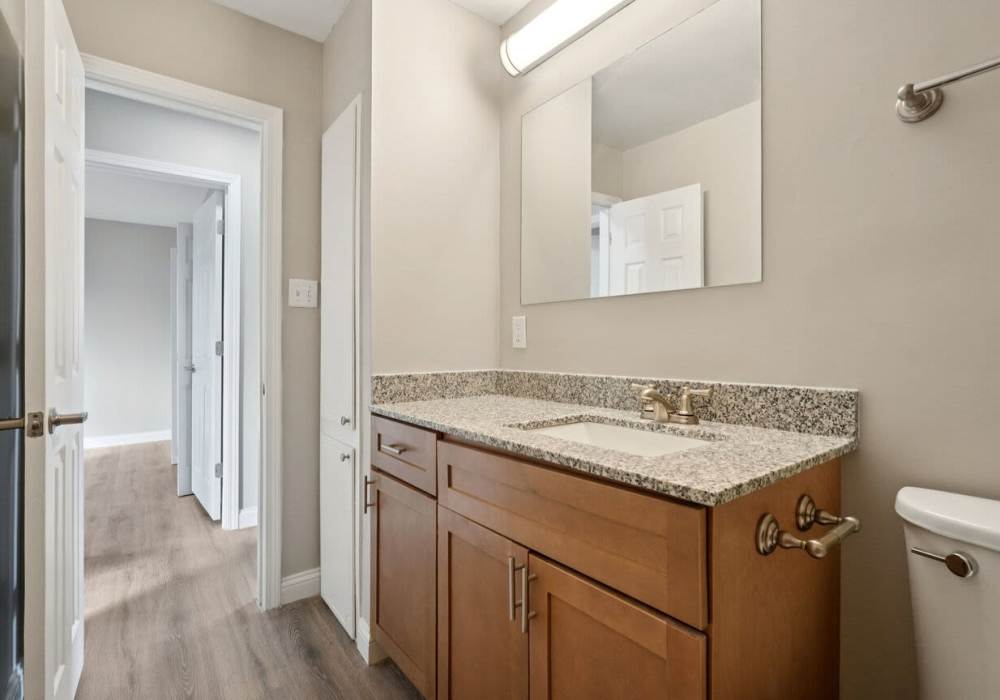 Bathroom with toilet , sink , vanity mirror and access to bedroom at Charleston Square Apartments in Columbus, Indiana