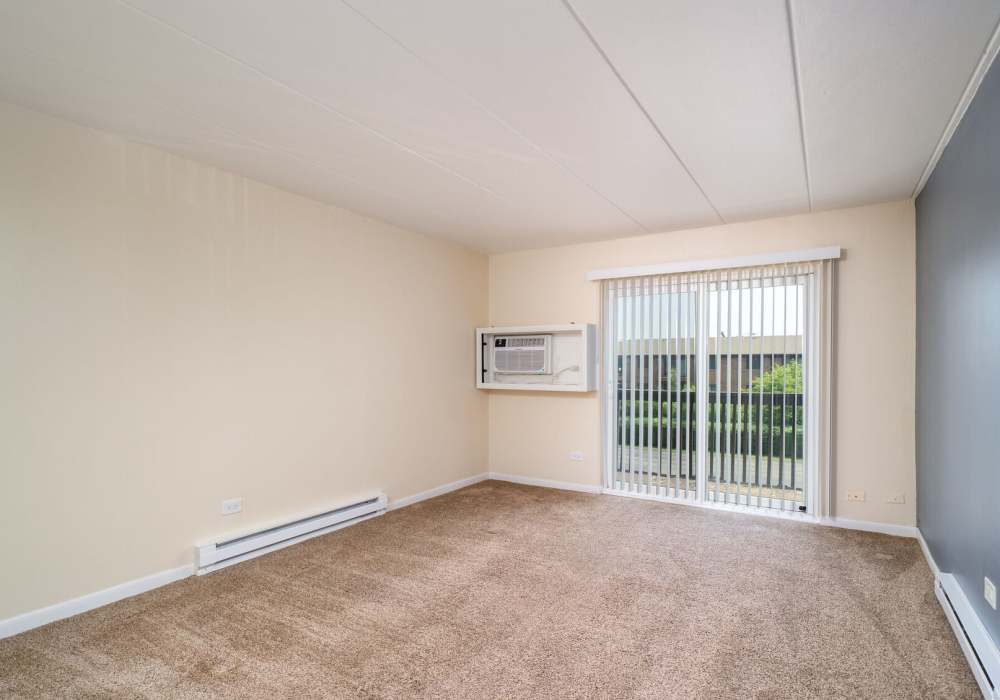 Living room room with carpet and sliding glass door at Regents Park Apartments in Bensenville, Illinois