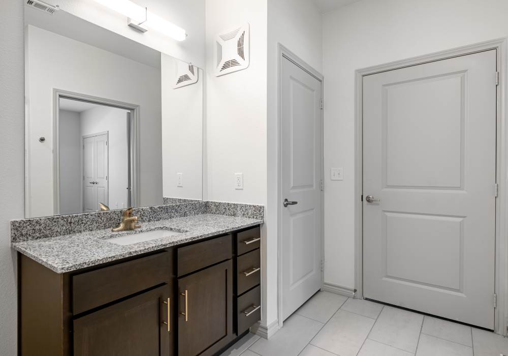 Modern bathroom with granite countertop and mirror at Terrace at Southern Oaks in Dallas, Texas