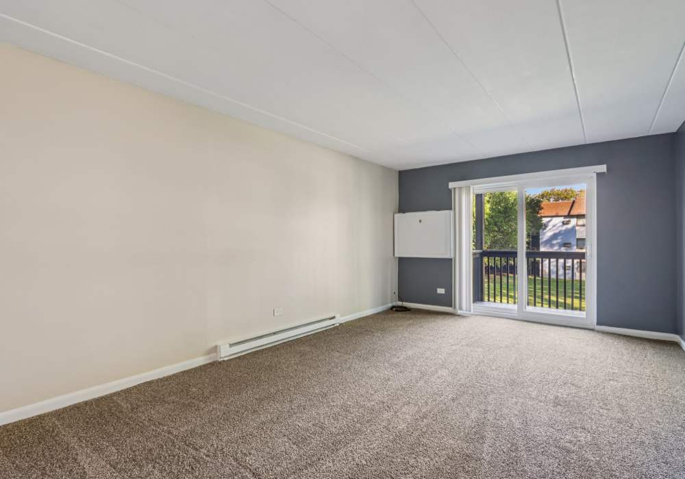 Living room with carpet and sliding door at Regents Park Apartments in Bensenville, Illinois