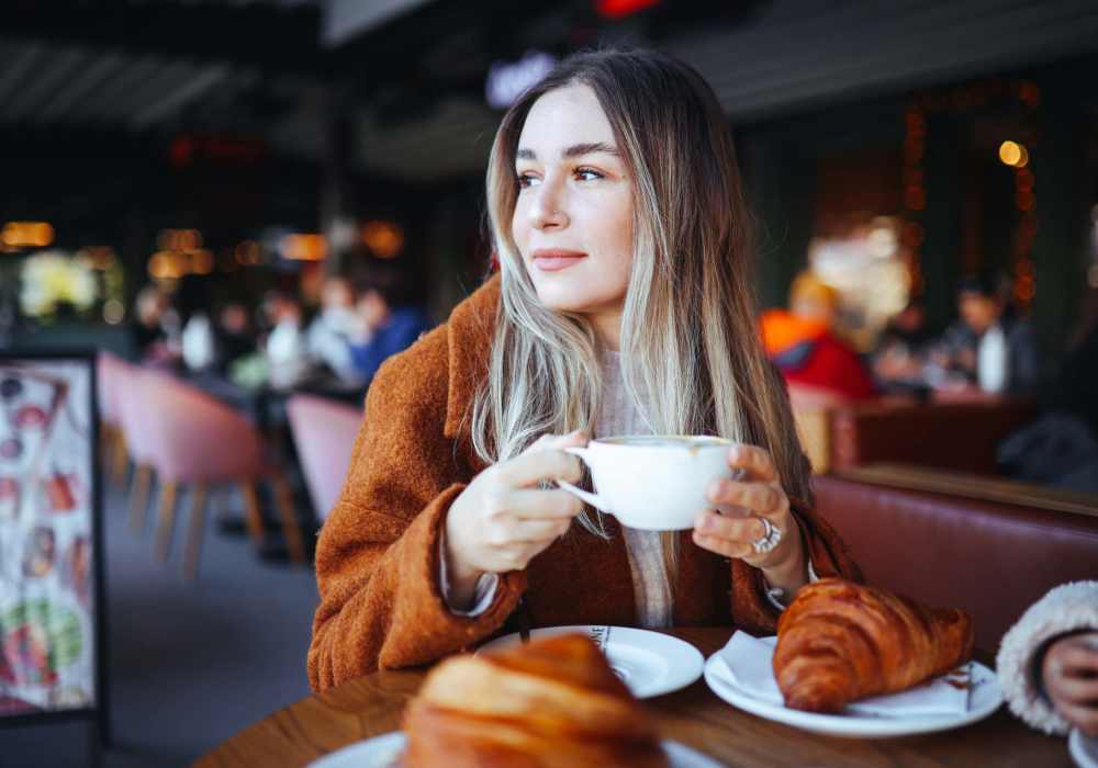 Woman holding cup with croissants on table at Terrace at Southern Oaks in Dallas, Texas