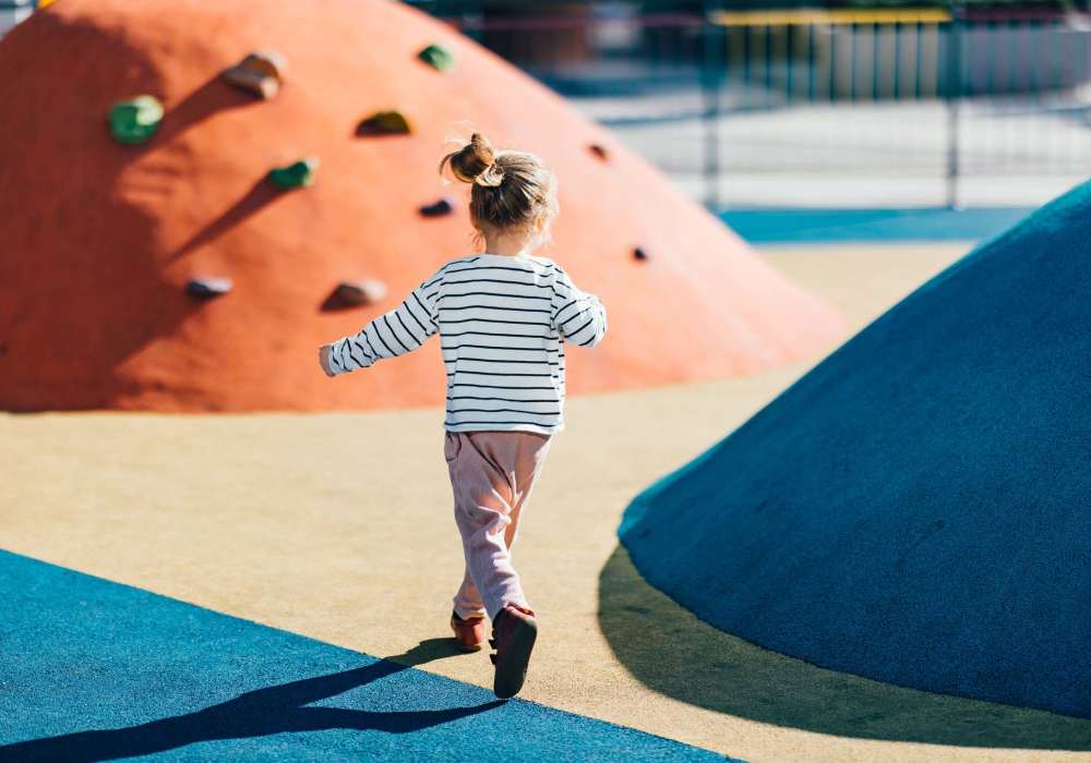 Child running on colorful playground with climbing hills at Terrace at Southern Oaks in Dallas, Texas