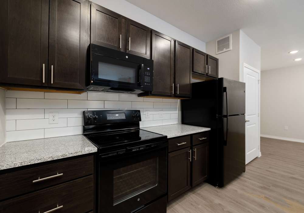Kitchen with black appliances and wood-style appliances at Preserve at Gresham Lake in Raleigh,North Carolina