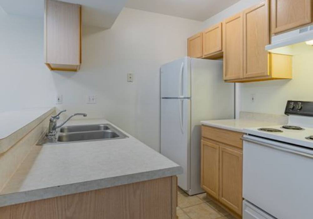 Compact kitchen with cabinets and appliances at North Road Townhomes in Scottsville, New York