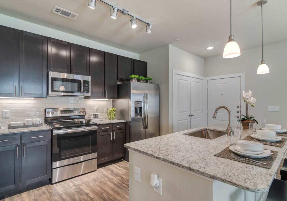 Kitchen with dark cabinets, stainless steel appliances and granite countertop at Southfork Lake in Manvel, Texas