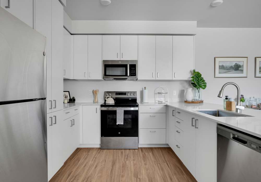 Apartment kitchen with stainless steel appliances, granite countertops, and wood-style flooring at Tilian Point in Woodburn, Oregon