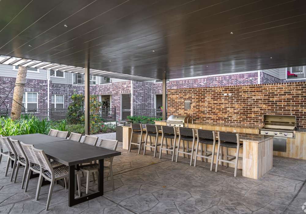 Covered outdoor kitchen and dining area featuring a long communal table at Charleston at Fannin Station in Houston, Texas