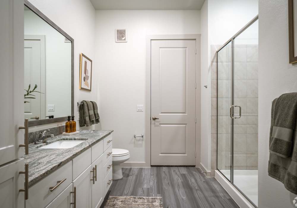 Modern apartment bathroom featuring an extended granite double vanity with dual undermount sinks at Charleston at Fannin Station in Houston, Texas