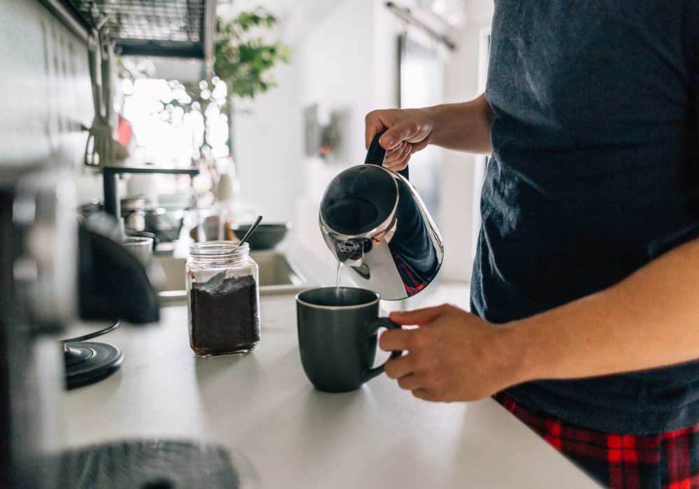 Man pouring coffee into a mug in a modern kitchen with bright lighting and stylish decor at Rincon Apartments in McAllen, Texas