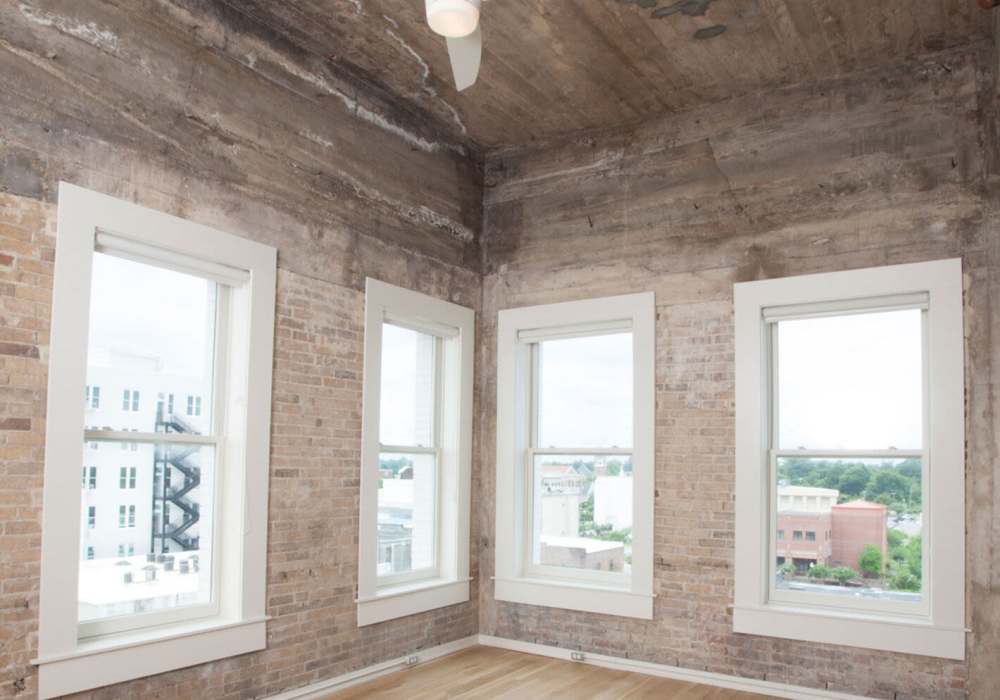 Three windows with white trim and brick walls at Hub City Lofts in Hattiesburg, Mississippi