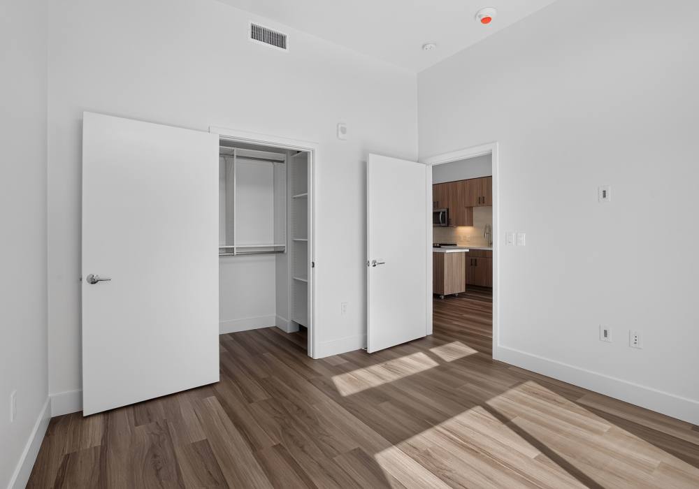 Empty bedroom with walk-in closet, double doors and view into kitchen at The Colton in Redwood City, California