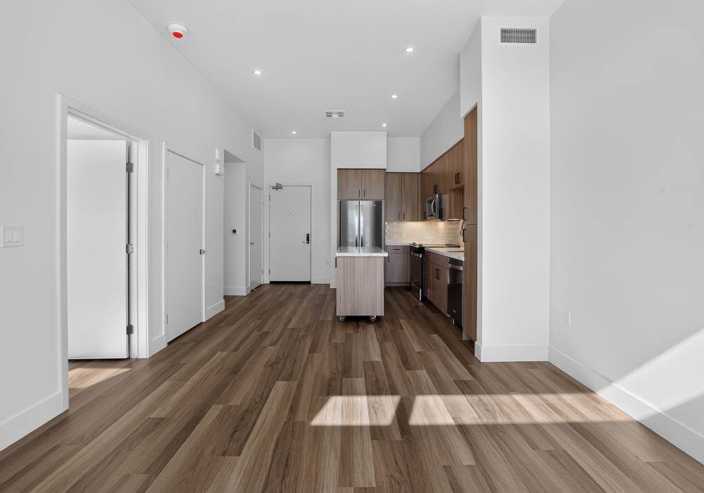 Long open living and dining space leading to kitchen with center island at The Colton in Redwood City, California