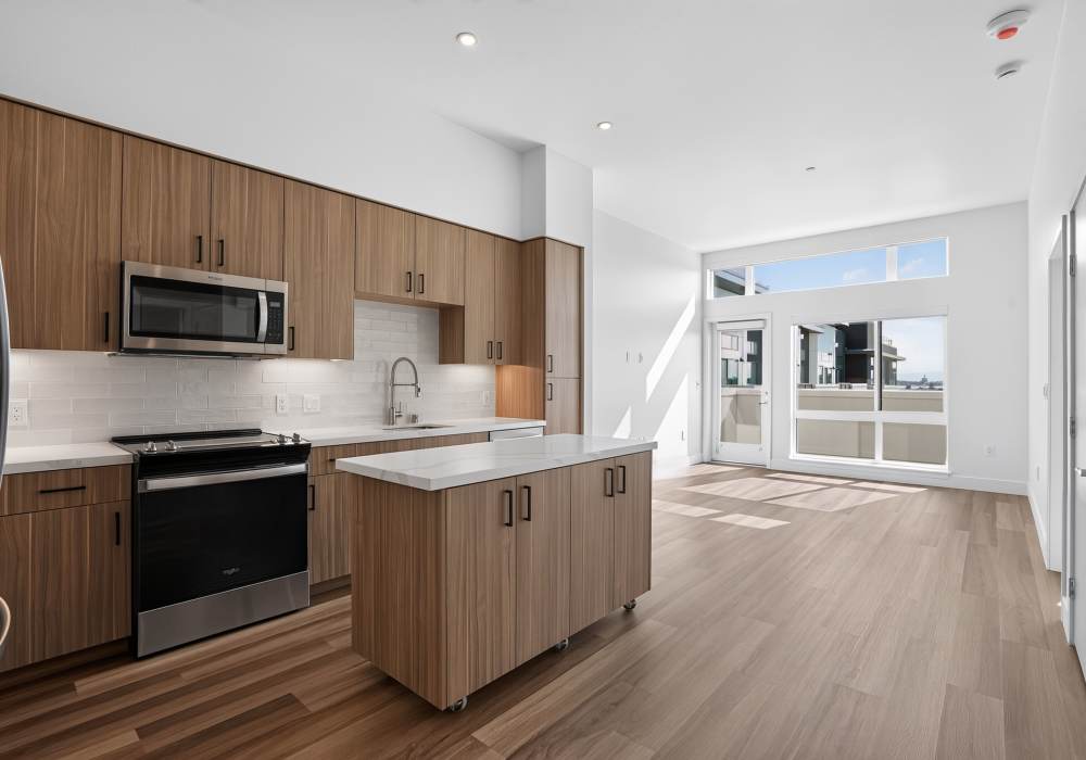 Open kitchen with wood cabinets, quartz island on casters and patio door at The Colton in Redwood City, California