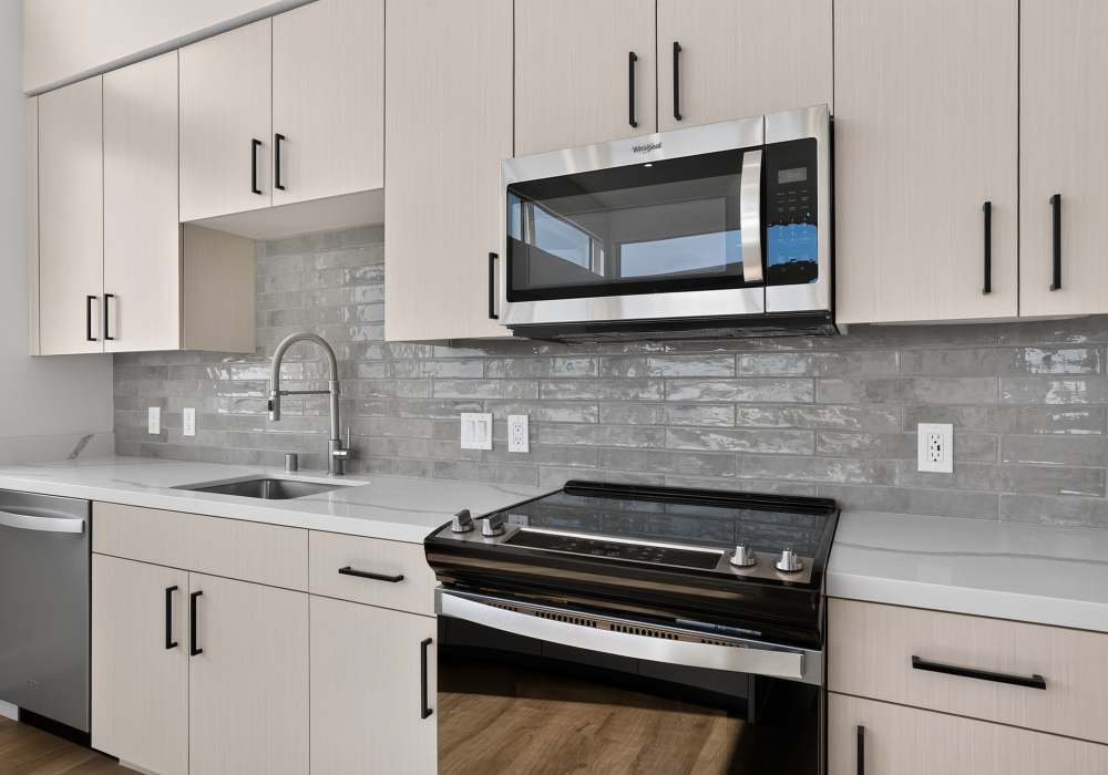Kitchen counter with stainless range, microwave and gray tile backsplash at The Colton in Redwood City, California