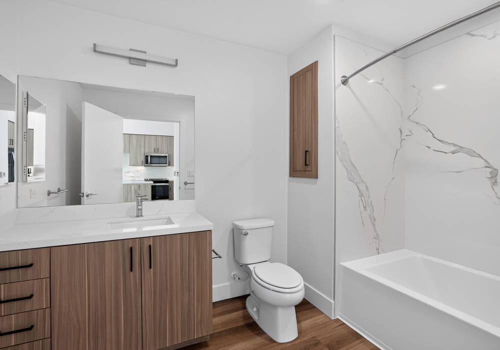 Bathroom with quartz vanity, large mirror and tub with marble surround at The Colton in Redwood City, California