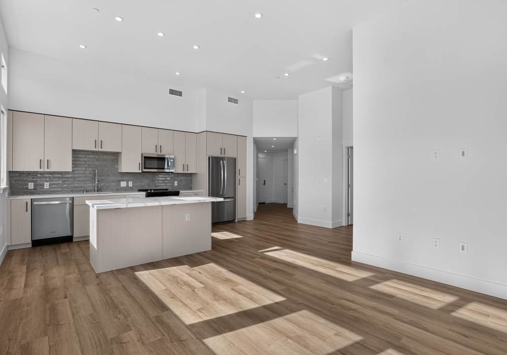 Open kitchen with light cabinets, gray backsplash, island and high ceiling at The Colton in Redwood City, California