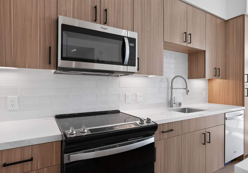 Kitchen counter with stainless range, microwave and white tile backsplash at The Colton in Redwood City, California