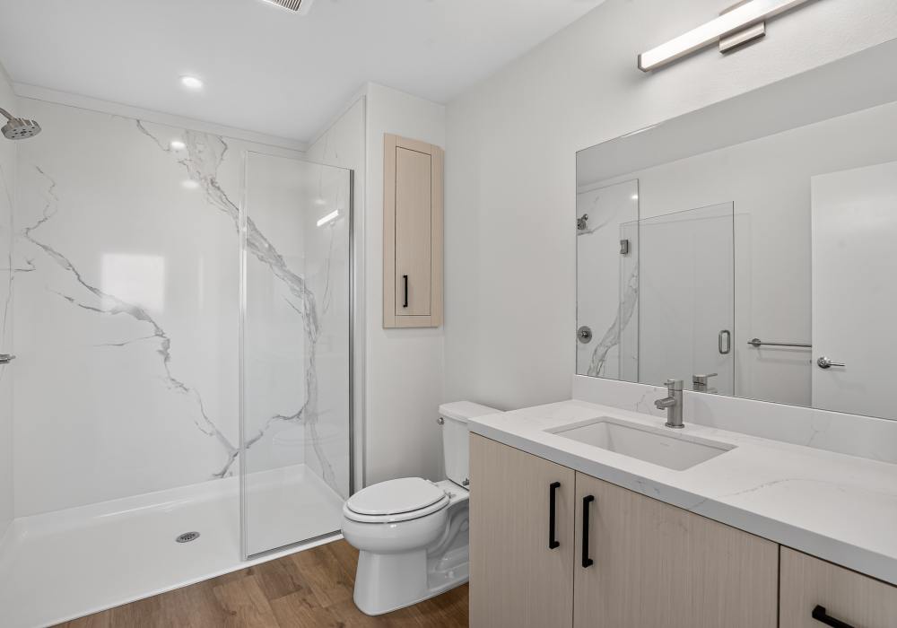 Bathroom with walk-in shower, quartz vanity and large mirror at The Colton in Redwood City, California