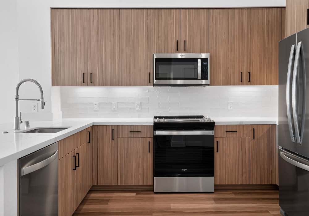Kitchen with wood cabinets, white tile backsplash and stainless appliances at The Colton in Redwood City, California