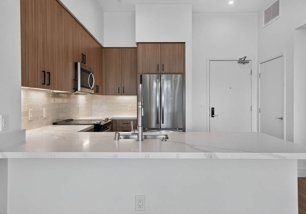Kitchen peninsula with quartz counter, stainless fridge and entry door at The Colton in Redwood City, California