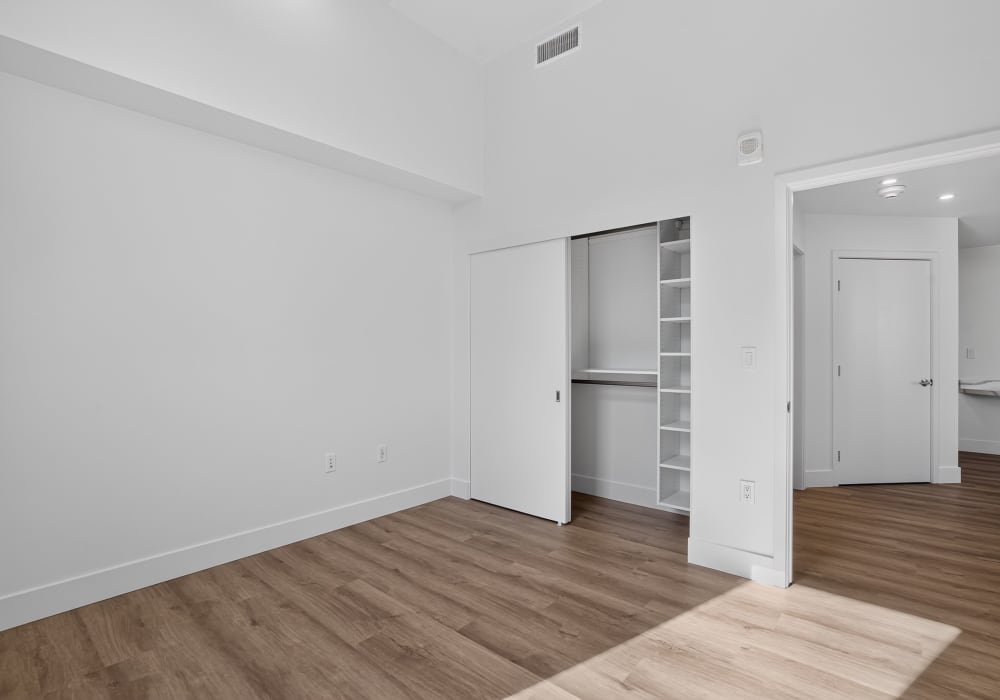 Empty bedroom with sliding-door closet, shelving and hall to kitchen at The Colton in Redwood City, California