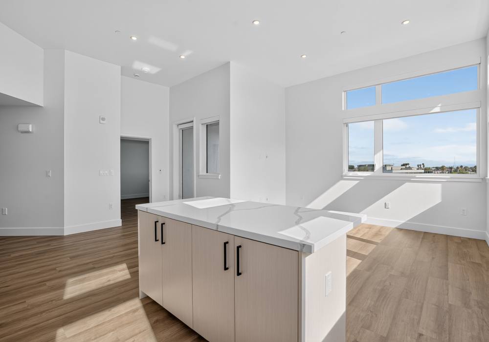 Open living space with quartz island, corner windows and plank flooring at The Colton in Redwood City, California