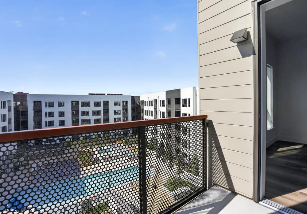 Balcony with perforated metal railing and view of nearby buildings at The Colton in Redwood City, California
