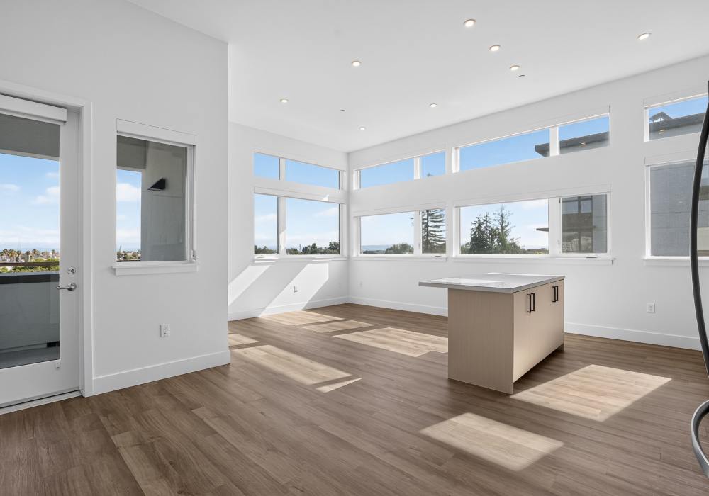 Sunlit corner living space with quartz island and wraparound windows at The Colton in Redwood City, California