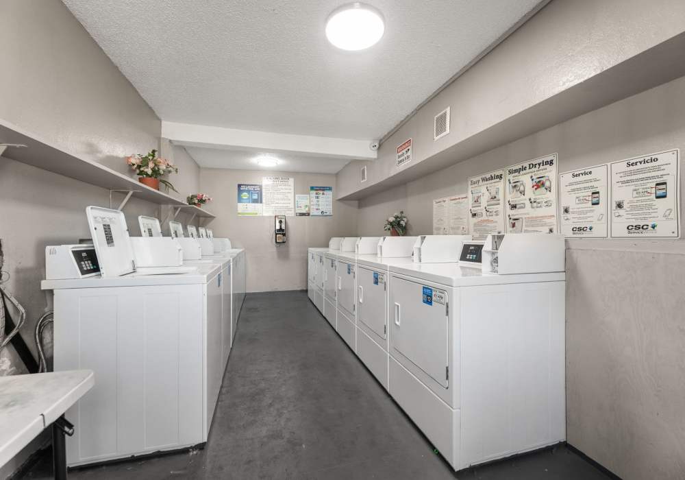 Laundry room with washers, stacked dryers and service instruction posters on the wall at Country Oaks in Weatherford, Texas